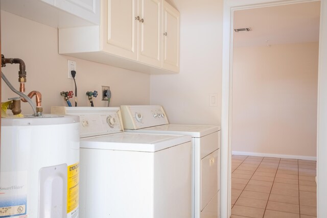 clothes washing area featuring electric water heater, light tile patterned floors, cabinets, and washer and dryer