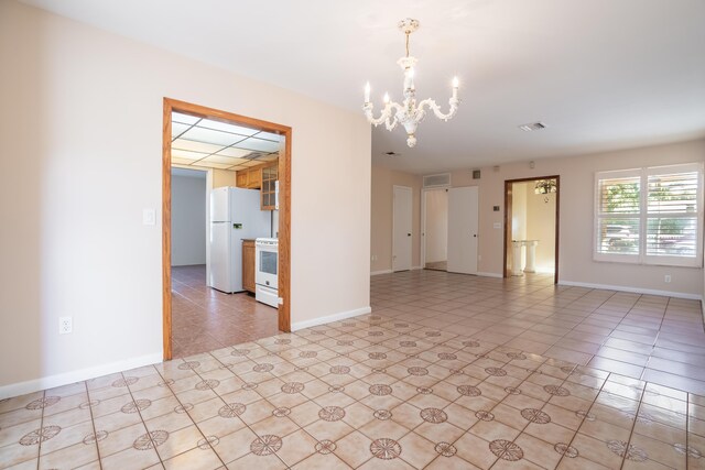 tiled empty room featuring an inviting chandelier