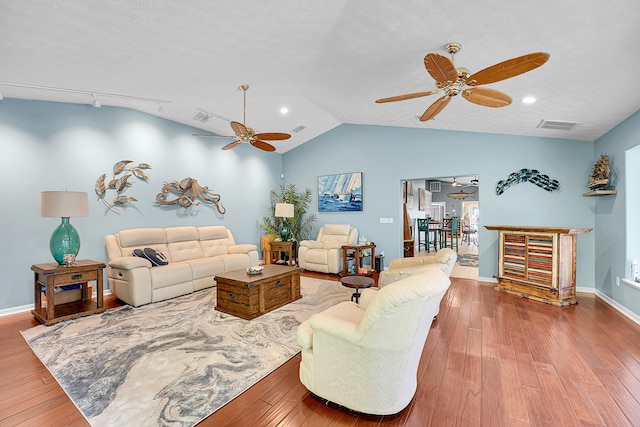 living room with hardwood / wood-style flooring, lofted ceiling, and a textured ceiling