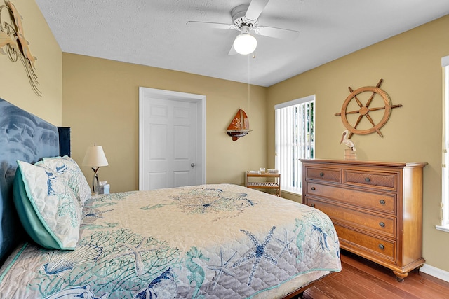 bedroom with ceiling fan, hardwood / wood-style floors, and a textured ceiling