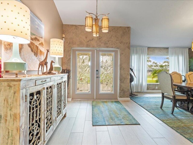 entrance foyer with light hardwood / wood-style floors, a chandelier, and french doors