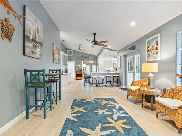 interior space featuring vaulted ceiling, ceiling fan, light hardwood / wood-style floors, a textured ceiling, and french doors