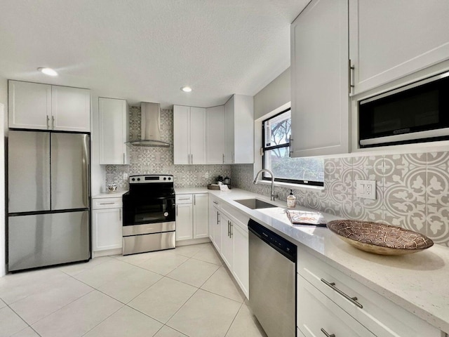 kitchen featuring white cabinets, wall chimney exhaust hood, stainless steel appliances, and a sink