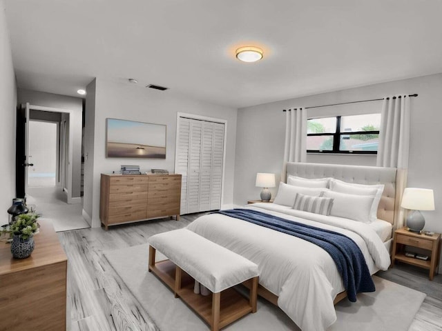 bedroom featuring light wood-style floors, visible vents, baseboards, and a closet