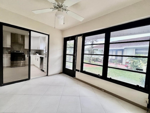 empty room featuring light tile patterned floors, a sink, a ceiling fan, and baseboards