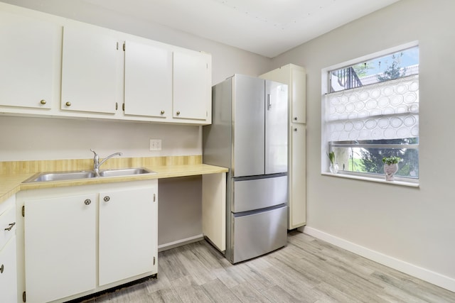 kitchen with white cabinetry, sink, stainless steel fridge, and light hardwood / wood-style flooring