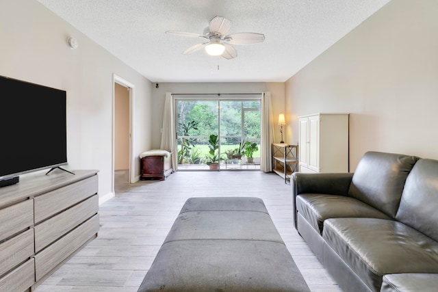 living room featuring ceiling fan, a textured ceiling, and light hardwood / wood-style floors