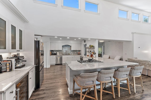 kitchen with a kitchen breakfast bar, stainless steel appliances, a center island, wine cooler, and white cabinets