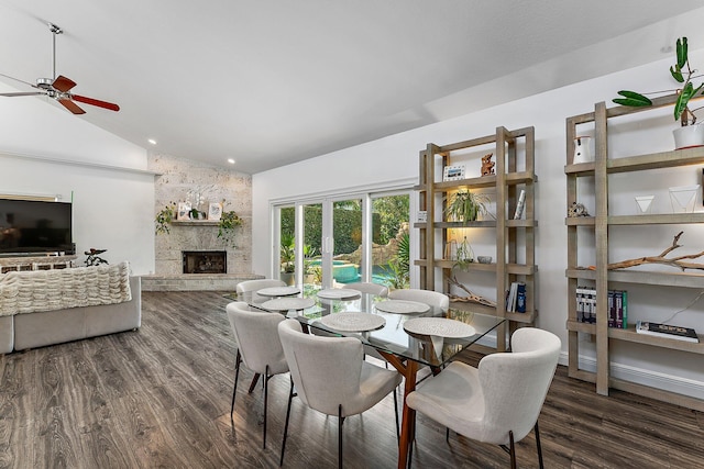 dining room featuring ceiling fan, a fireplace, dark hardwood / wood-style flooring, and vaulted ceiling