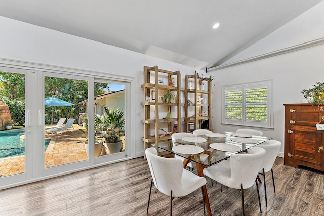 dining area with wood-type flooring and vaulted ceiling