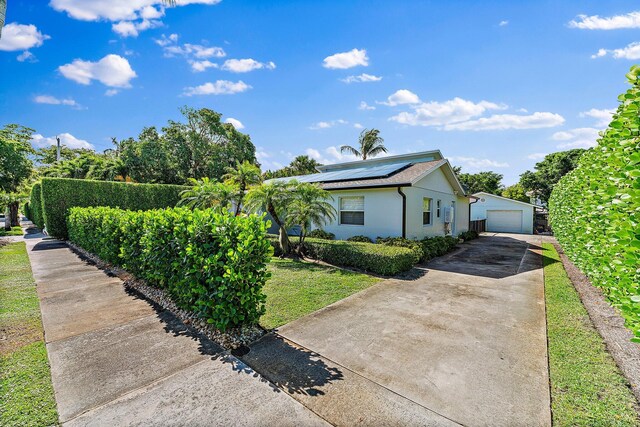 ranch-style home with solar panels, an outbuilding, a garage, and a front yard