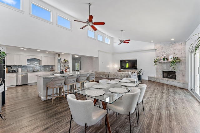 dining space featuring ceiling fan, wood-type flooring, a fireplace, and sink