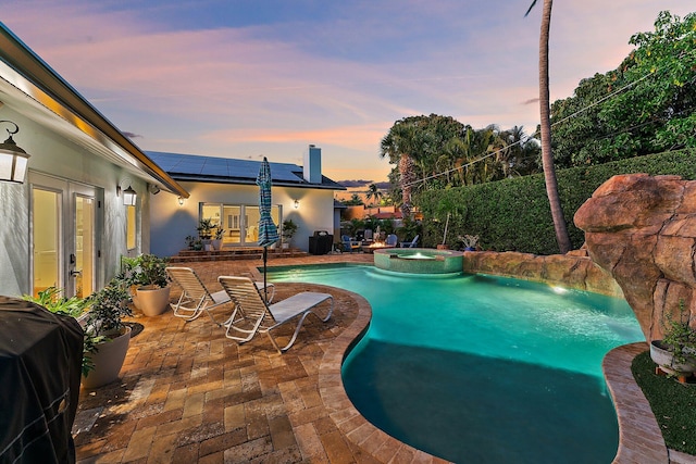 pool at dusk featuring french doors, an in ground hot tub, grilling area, and a patio