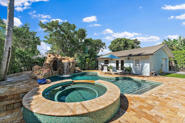 view of pool with an in ground hot tub, pool water feature, an outbuilding, and a patio area