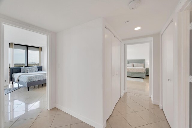 corridor featuring recessed lighting, baseboards, and light tile patterned flooring