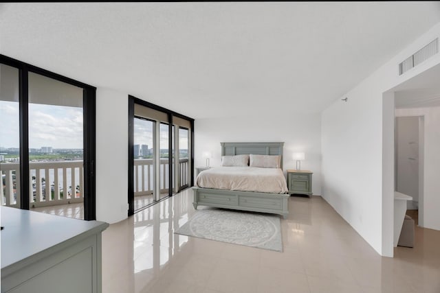 bedroom featuring visible vents, light tile patterned flooring, a textured ceiling, a wall of windows, and access to outside