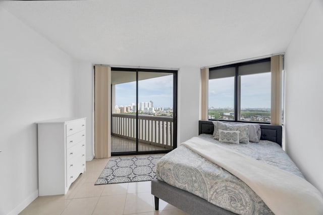 bedroom with access to exterior, a view of city, tile patterned flooring, and baseboards