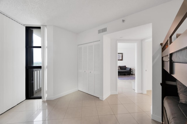 interior space with visible vents, a textured ceiling, baseboards, and light tile patterned floors