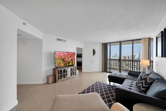 living area featuring light tile patterned floors, baseboards, visible vents, a textured ceiling, and floor to ceiling windows