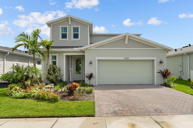 view of front of home featuring a garage, a front lawn, decorative driveway, and stucco siding