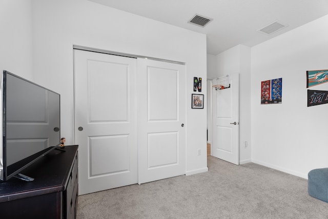 bedroom with a closet, visible vents, light carpet, and baseboards