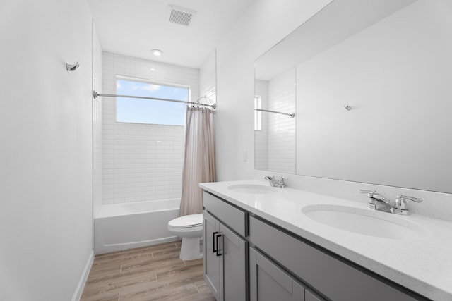 full bathroom with shower / bathtub combination with curtain, visible vents, a sink, and wood finished floors