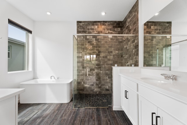 bathroom featuring wood finish floors, a soaking tub, vanity, and a shower stall