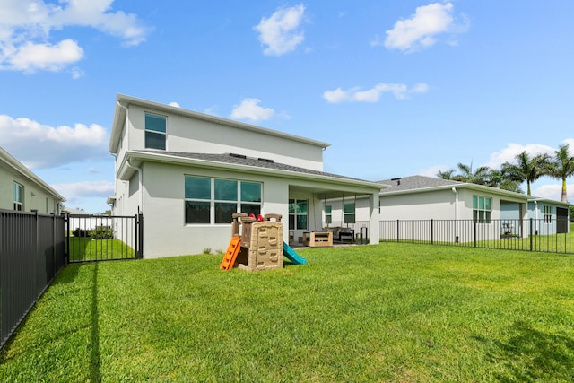 rear view of property with stucco siding, a fenced backyard, a playground, and a yard