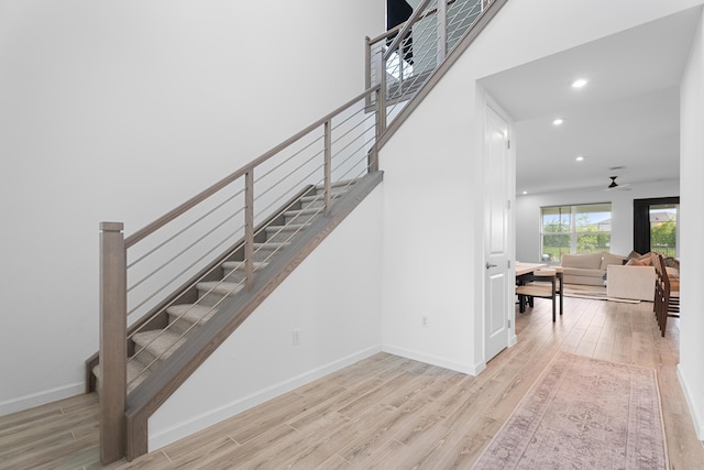 stairs with recessed lighting, wood finished floors, a ceiling fan, and baseboards