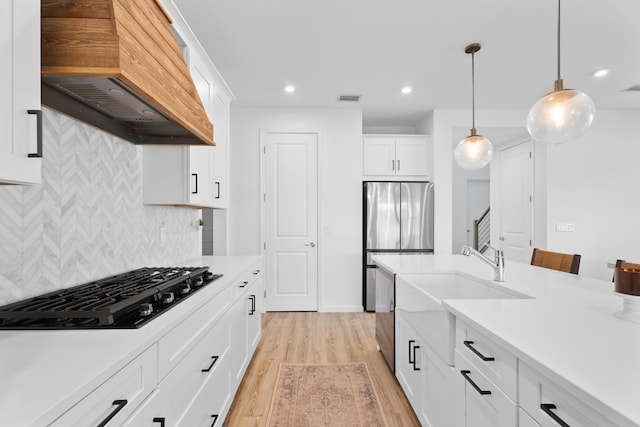 kitchen featuring black gas cooktop, white cabinets, light countertops, custom exhaust hood, and pendant lighting