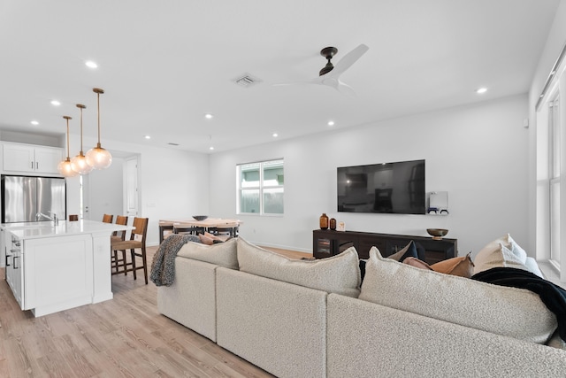 living area featuring visible vents, baseboards, light wood-style flooring, ceiling fan, and recessed lighting