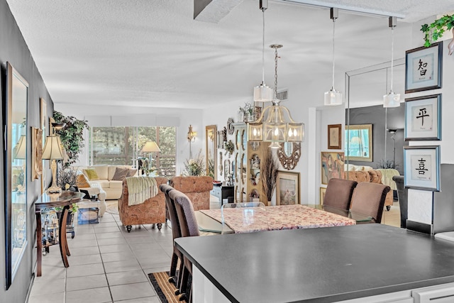 dining space with track lighting, light tile patterned floors, and a textured ceiling