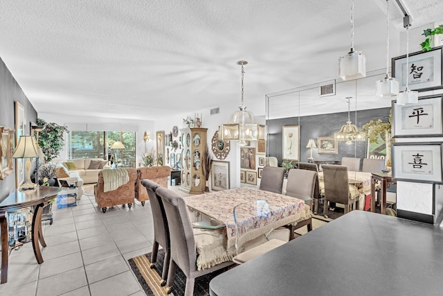 dining space featuring a textured ceiling, a notable chandelier, track lighting, and light tile patterned flooring