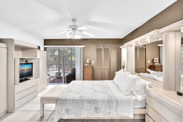 bedroom with a textured ceiling, light tile patterned floors, a closet, access to exterior, and ceiling fan