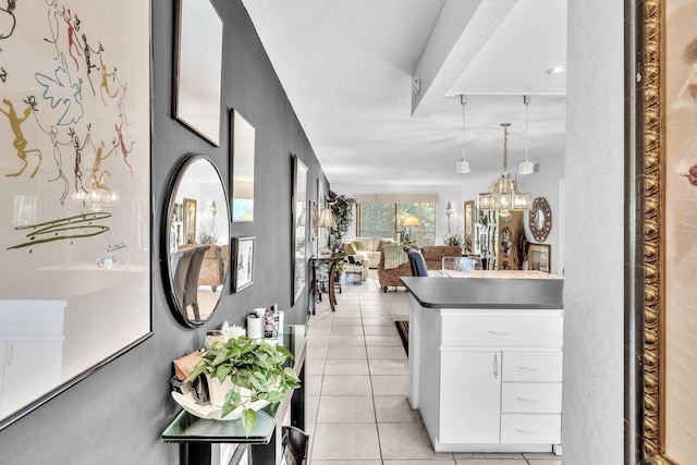 kitchen featuring white cabinets, hanging light fixtures, light tile patterned floors, and a textured ceiling