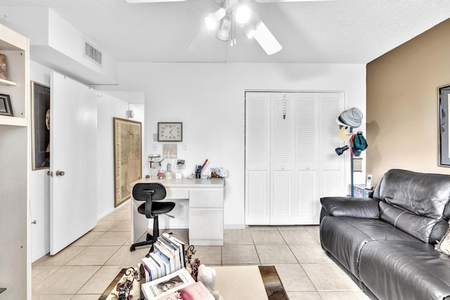 living room with a textured ceiling, ceiling fan, and light tile patterned flooring