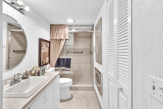 bathroom with a shower with door, vanity, a textured ceiling, tile patterned flooring, and toilet