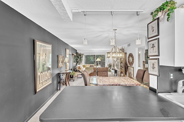 interior space with a textured ceiling, rail lighting, and a notable chandelier