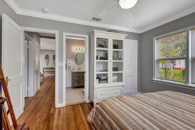 bedroom featuring ornamental molding, ensuite bath, ceiling fan, and hardwood / wood-style floors