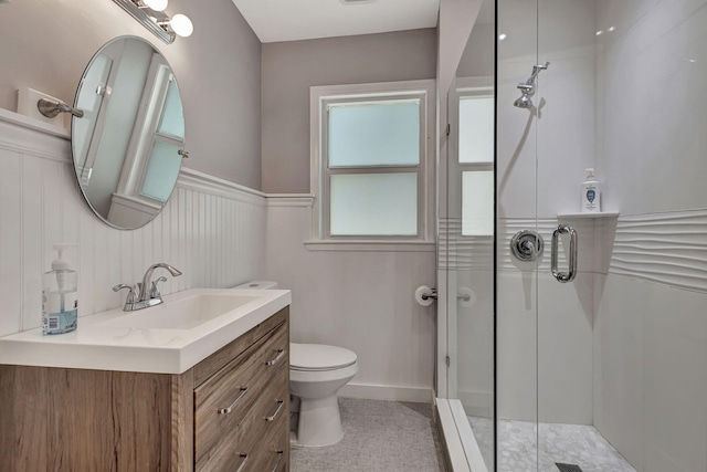 bathroom featuring a shower with shower door, vanity, tile patterned flooring, and toilet