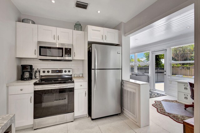 kitchen featuring white cabinets, decorative backsplash, appliances with stainless steel finishes, and light tile patterned floors