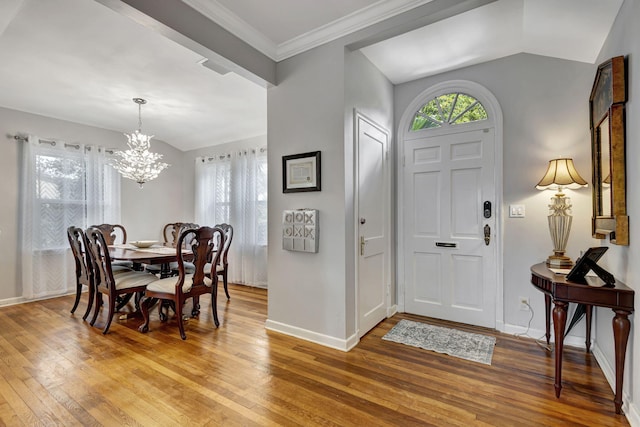 entrance foyer with hardwood / wood-style flooring, vaulted ceiling, and a chandelier