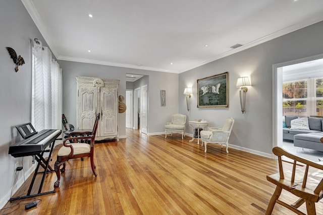 living area featuring crown molding and light hardwood / wood-style flooring