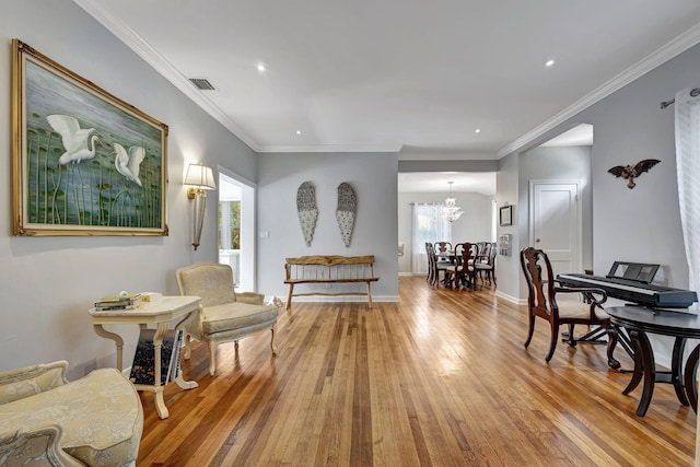 sitting room featuring light hardwood / wood-style flooring, an inviting chandelier, and crown molding