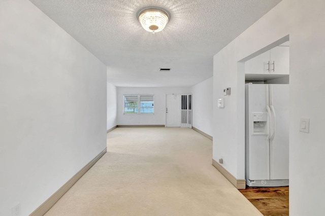 hallway with light carpet and a textured ceiling