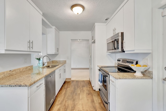 kitchen featuring light wood-type flooring, a textured ceiling, sink, white cabinetry, and appliances with stainless steel finishes