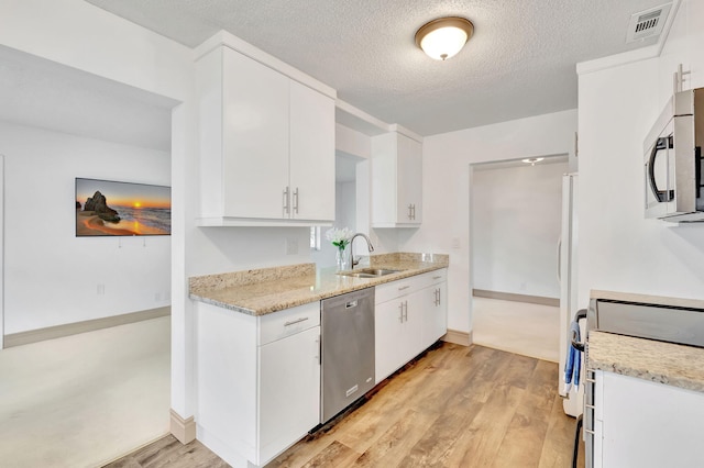 kitchen featuring appliances with stainless steel finishes, sink, white cabinets, and light hardwood / wood-style floors