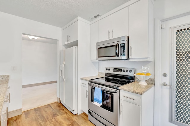 kitchen with appliances with stainless steel finishes, a textured ceiling, light hardwood / wood-style flooring, and white cabinets