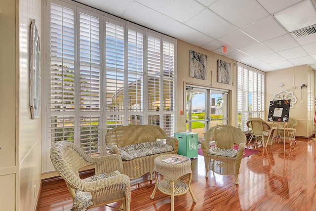 sitting room with a drop ceiling, french doors, and hardwood / wood-style flooring