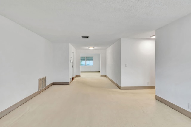 carpeted empty room with a textured ceiling